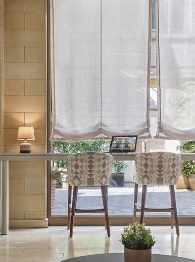 Window desk with patterned bar stools and a laptop