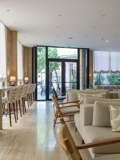 Lounge with long tables and armchairs by the glass entrance
